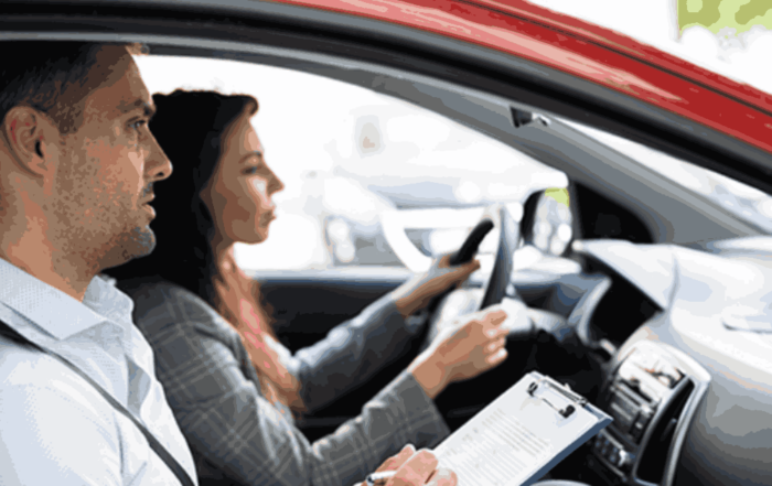 Alumno realizando un examen práctico de conducir en un coche de autoescuela acompañado por un examinador de tráfico.